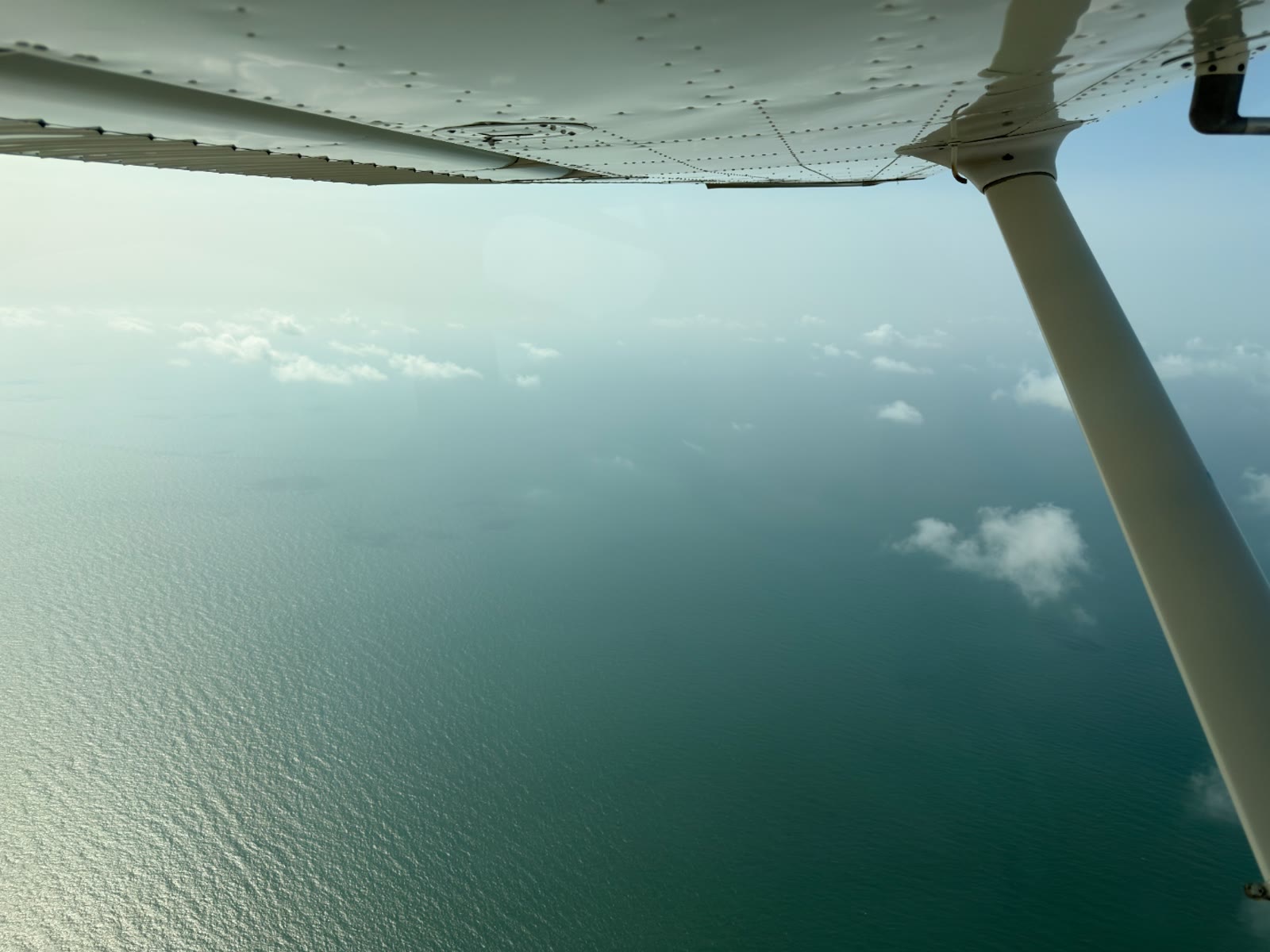 Scattered low clouds over the Gulf Coast seen from beneath the wing of a Cessna 172 during a lesson from KLVJ.